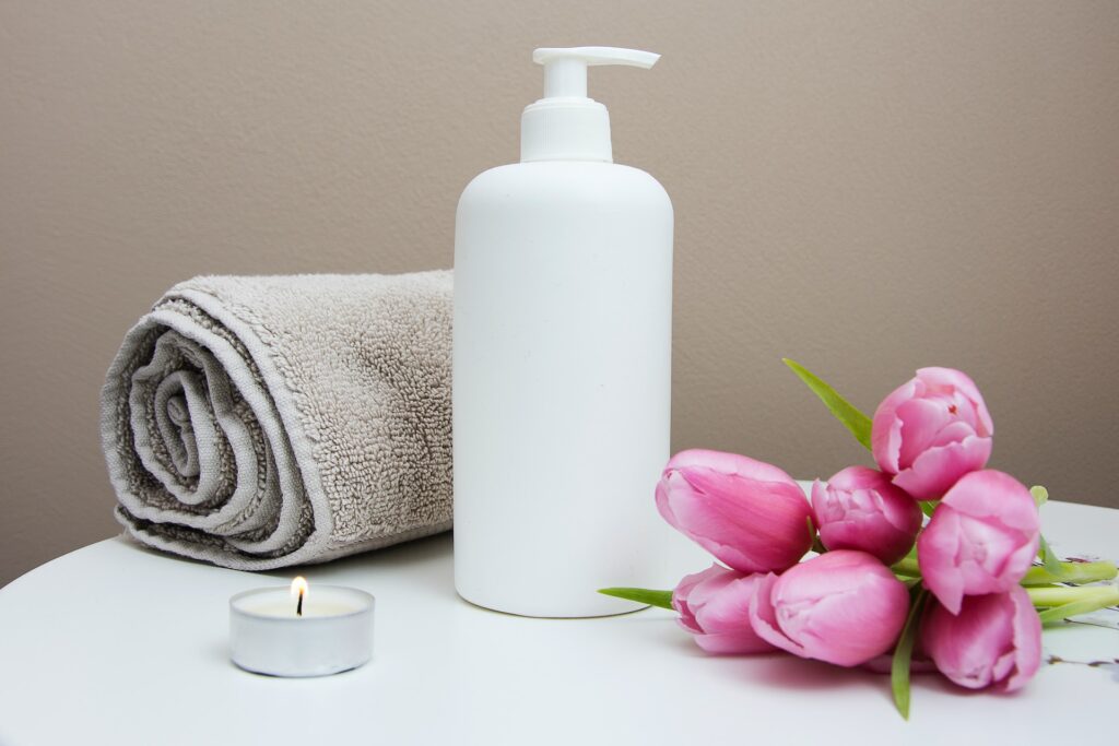 A towel, candle, flowers and lotion upon a table.