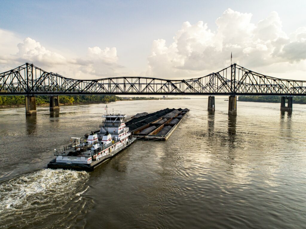 A special transportation ship, transporting goods on a river, going under a bridge.